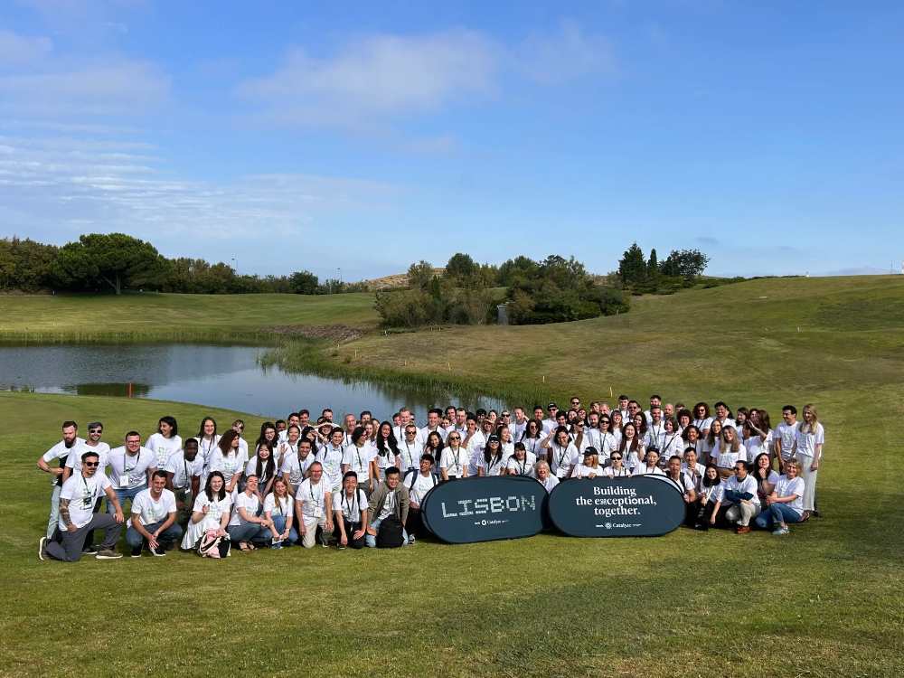 Large ideals team gathered outdoors during a company retreat organised by NextRetreat, posing for a group photo beside a lake and golf course.